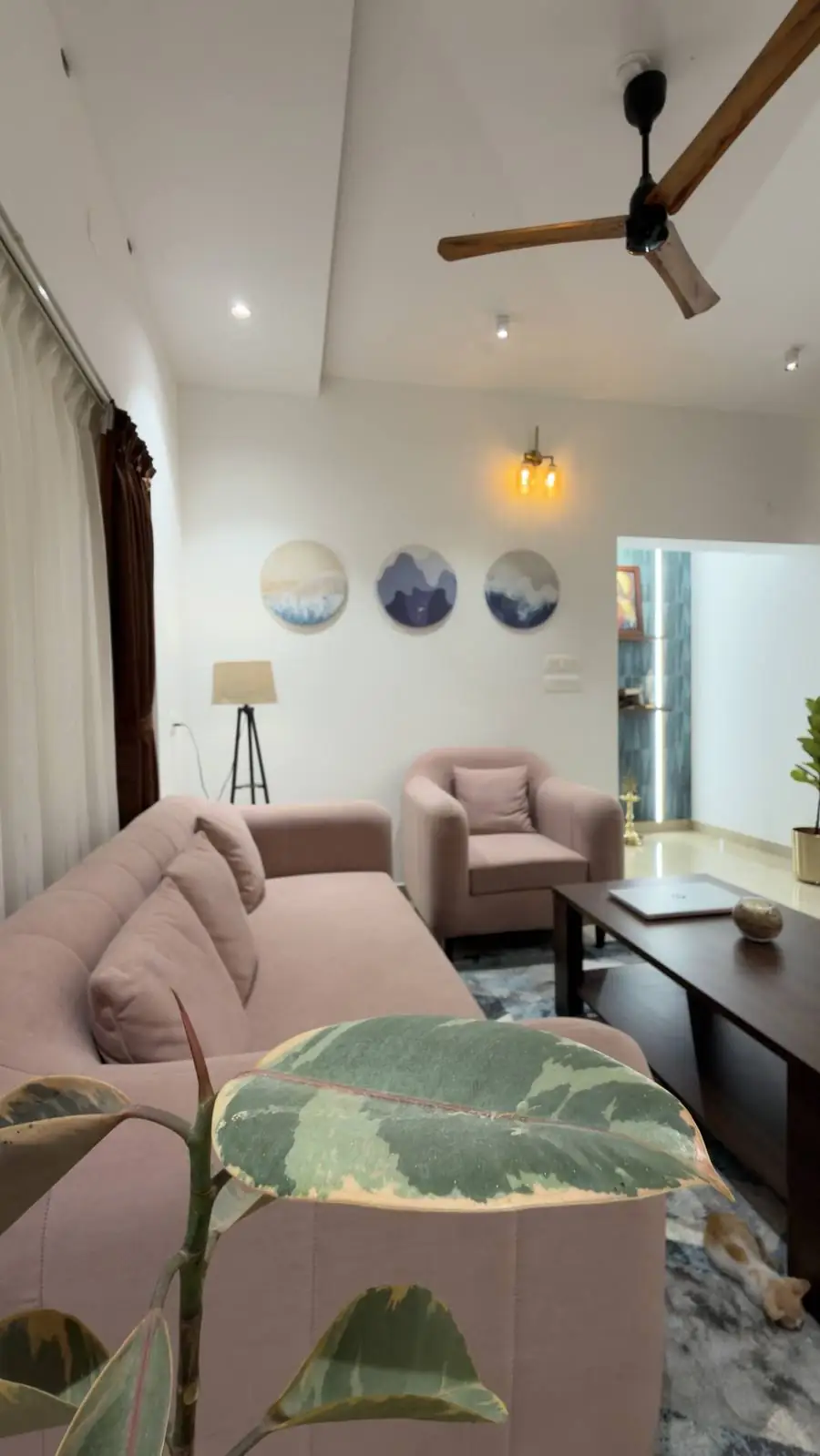 Living room with blush sofas, round wall art and a wooden fan